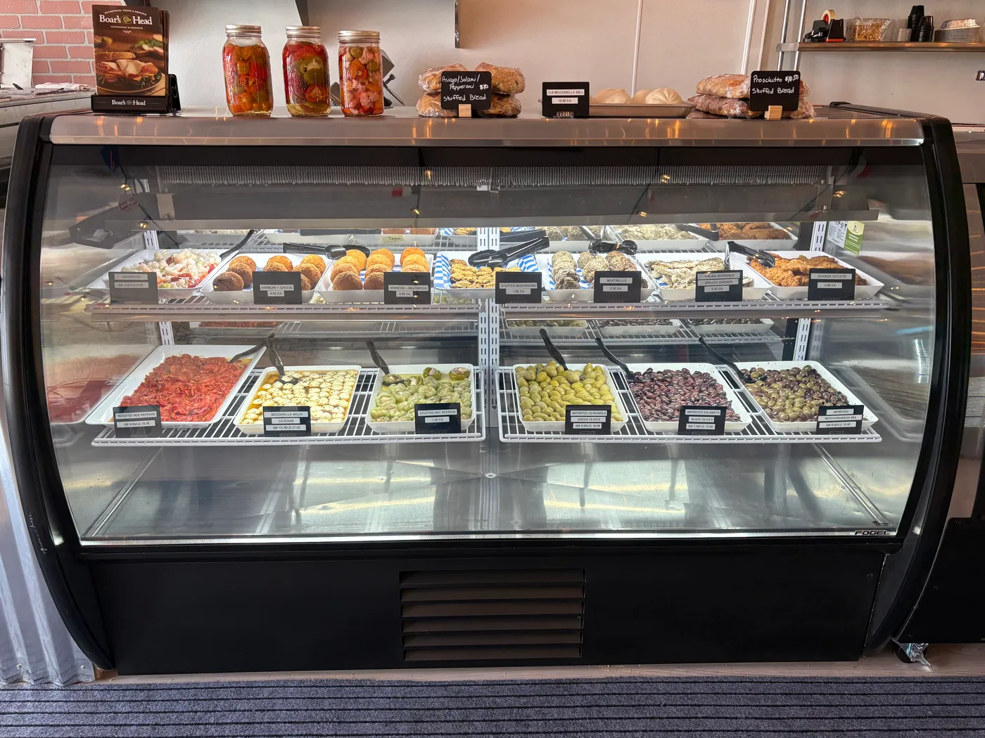 Zio's Market prepared foods case with arancini, meatballs, olives, and roasted peppers