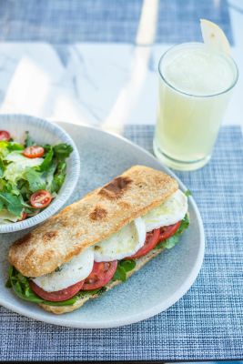 Delicious Caprese sandwich with fresh salad and lemonade on a sunny day.